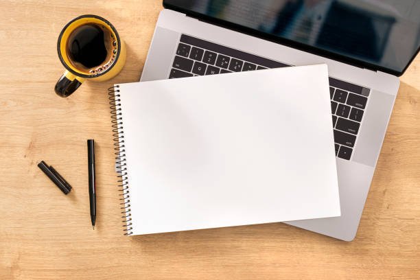 istock Online work concept Blank notebook with laptop and cup coffee on wooden table top view 1217078019