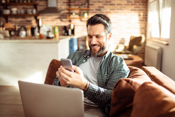 giovane che usa un telefono a casa - navigare in internet foto e immagini stock