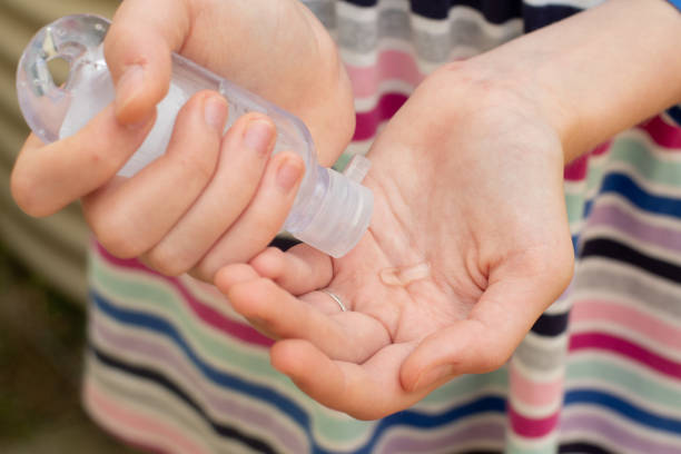 una ragazza con un abito a righe che applica disinfettante per le mani per proteggersi dal coronavirus - pompa daria foto e immagini stock