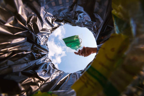 istock Face mask pack in zip lock before throw into the trash. With a worm view from the inside of the trash bin. 1217083929