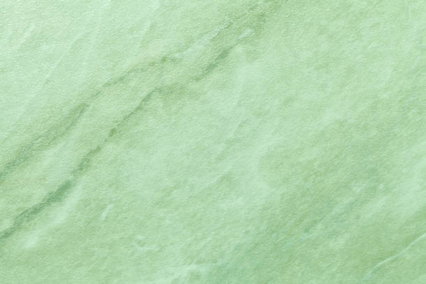 Texture of light green marble with olive lines of a pattern, macro background. Pastel color stone backdrop from mineral tile, closeup.