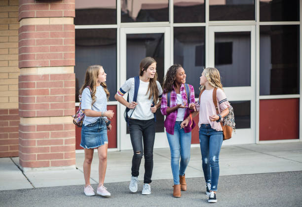 groupe de jeunes amies et étudiants parlant ensemble pendant qu’ils marchent à l’école à la maison pour la journée - smart casual outdoors friendship happiness photos et images de collection