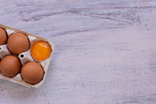 istock Fresh raw chicken eggs in egg carton/ Broken egg yolk/ Conceptual image of healthy breakfast/ Food background - Image 1217089254