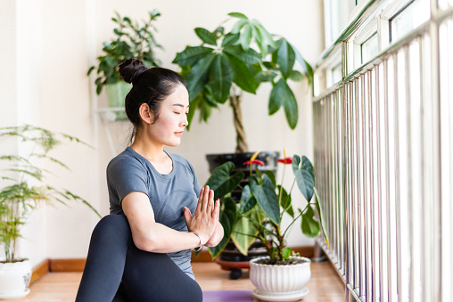 Mujer joven asiática practicando yoga en la sala de estar photo