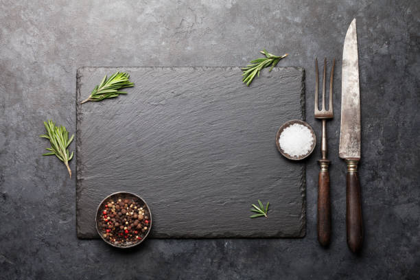 tavola in pietra con spezie e utensili - rosemary food herb cooking foto e immagini stock