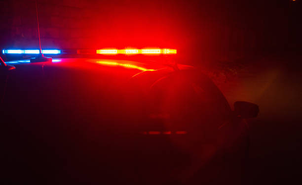 coche de policía con luces rojas y azules parpadeantes en el fondo vacío de la calle nocturna, escena del crimen, patrullando la ciudad, luchar contra el saqueo durante la cuarentena. - police lights fotografías e imágenes de stock