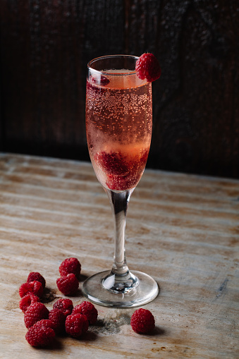 A glass of raspberry champagne on rustic background