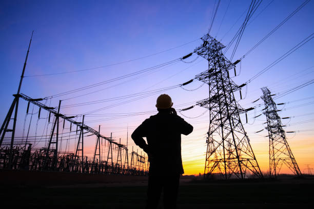 istock Electricity workers and pylon silhouette 1217093822