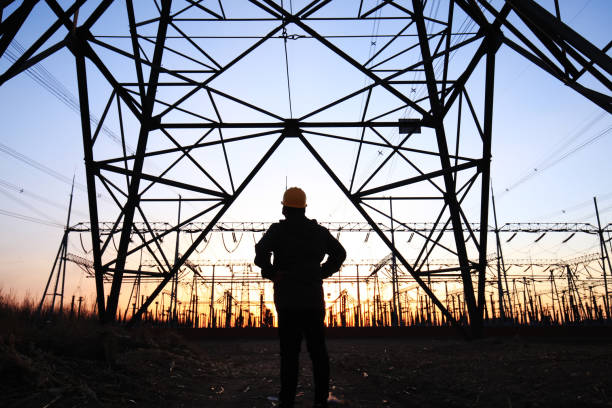 istock Electricity workers and pylon silhouette 1217093907