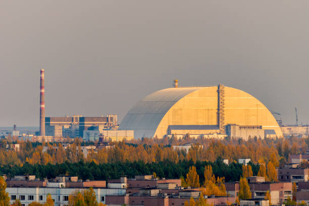 vista aerea dalla cima di un grattacielo abbandonato a pripyat, zona di esclusione di chernobyl con il blocco del reattore esploso 4, coperto dal nuovo sarcofago, all'orizzonte - sentinels of the tomb foto e immagini stock