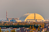 Aerial view from the top of an abandoned apartment skyscraper in Pripyat, Chernobyl Exclusion Zone with the exploded reactor block 4, covered by the new sarcophagus, on the horizon