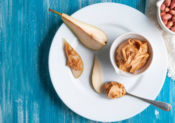 istock White cup with peanut butter. On a large white plate with a sliced ​​pear.
Flat lay composition. View from above. Blue wooden background. Space for text. 1217096002