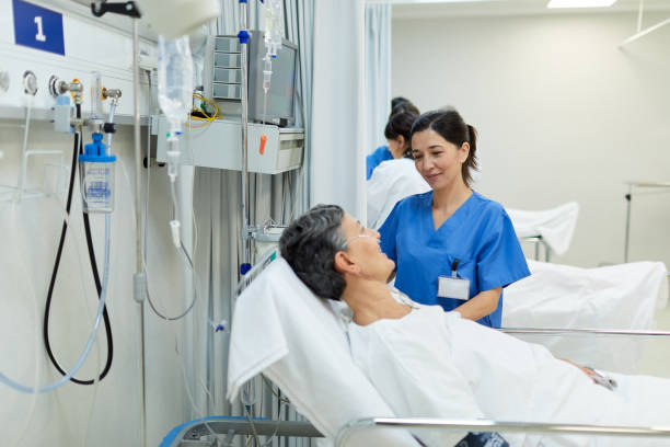 eine junge krankenschwester hört einem patienten in der postoperativen station zu. - operative stock-fotos und bilder