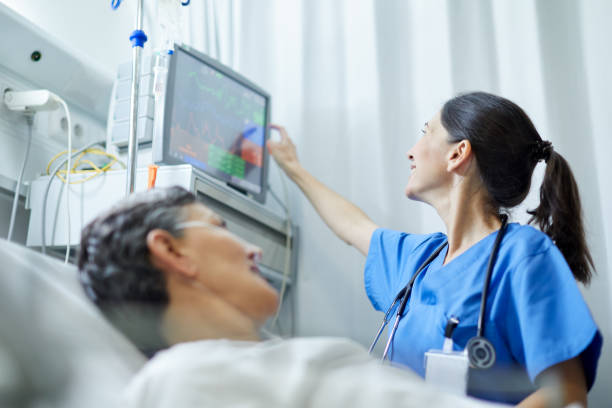 eine krankenschwester, die sich die vitalzeichen anschaut, überwacht. - hospital patient bed doctor stock-fotos und bilder