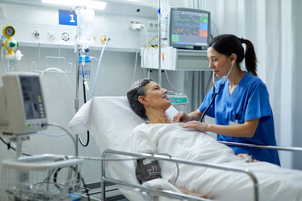 A female nurse is listening with a stethoscope the heart bit of a patient. Hospital health care and medicine. triage stock pictures, royalty-free photos & images