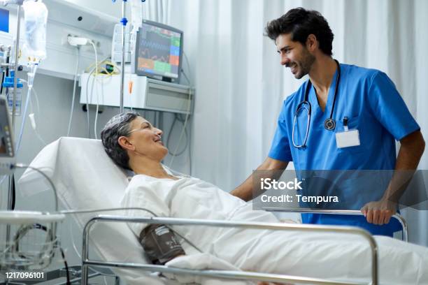 A Male Nurse Is Listening A Patient In The Recovery Area Stock Photo - Download Image Now