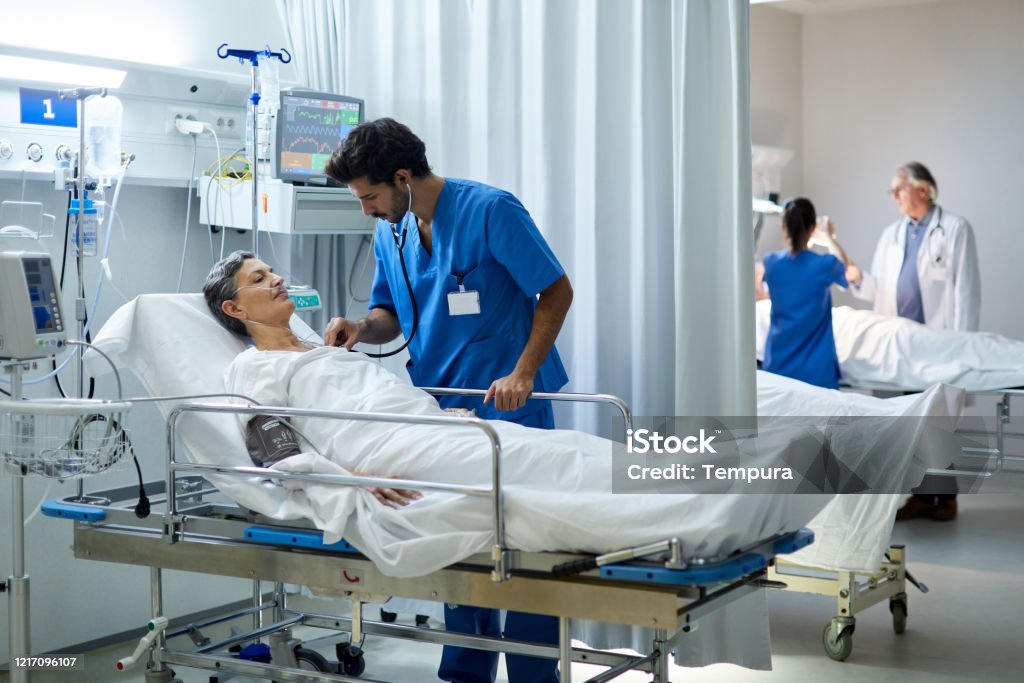 A male nurse is listening with a stethoscope the heart bit of a patient. Hospital health care and medicine. Hospital Stock Photo