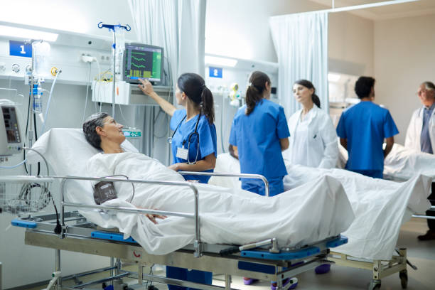 Wide view of the intensive care unit, a nurse looking at the vital signs monitor. Hospital health care and medicine. triage stock pictures, royalty-free photos & images