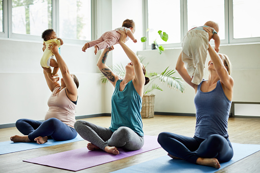 Full length shot of a young group of mothers sitting with their babies during a baby yoga class indoors
