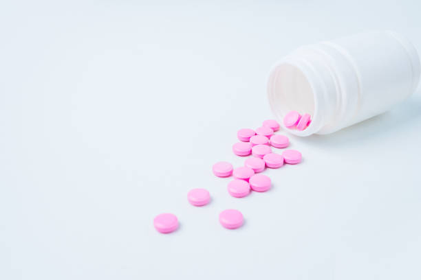 istock pink pills are poured out of plastic packaging on a white background with copy space for text. Opioid epidemic, painkillers and drug abuse concept 1217097162