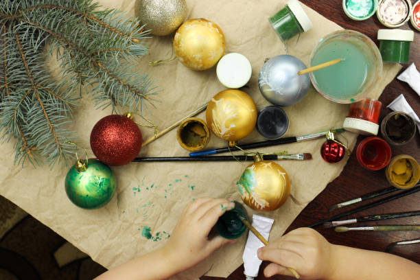 istock The child draws a pattern on a Christmas toy. Hands close-up holding a brush. 1217097707