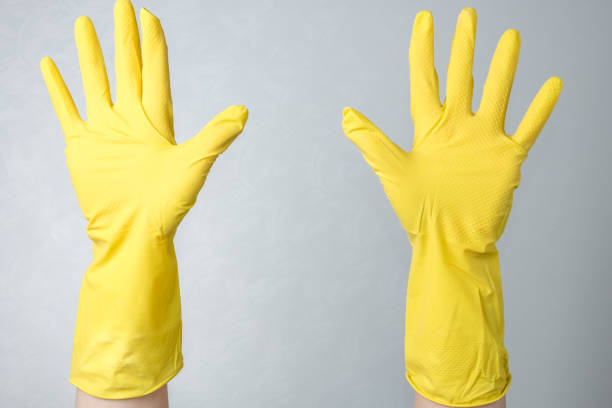 istock Hands in yellow rubber gloves against a white wall background 1217098023