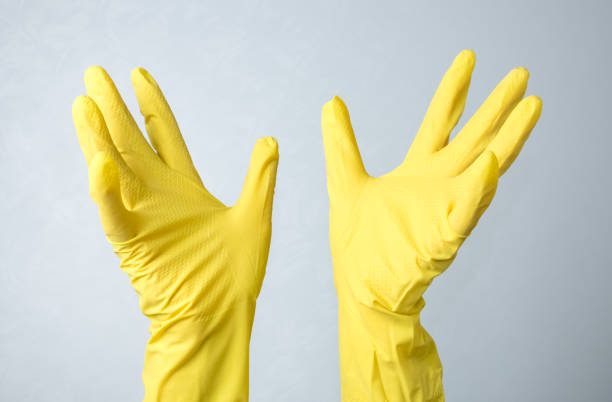 istock Hands in yellow rubber gloves against a white wall background 1217098048