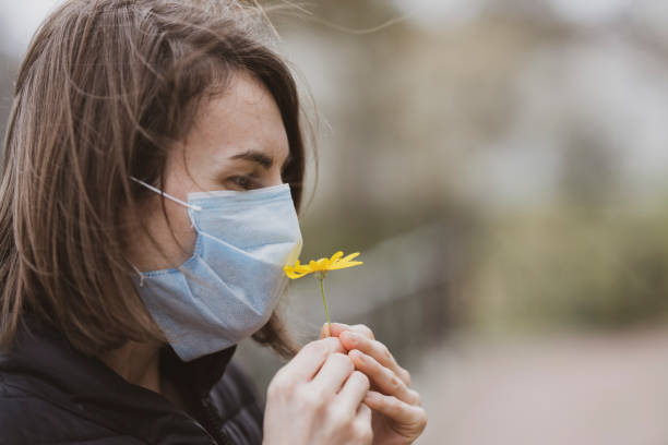 femme utilisant le masque facial pendant l’éclosion de coronavirus - temperate flower photos et images de collection