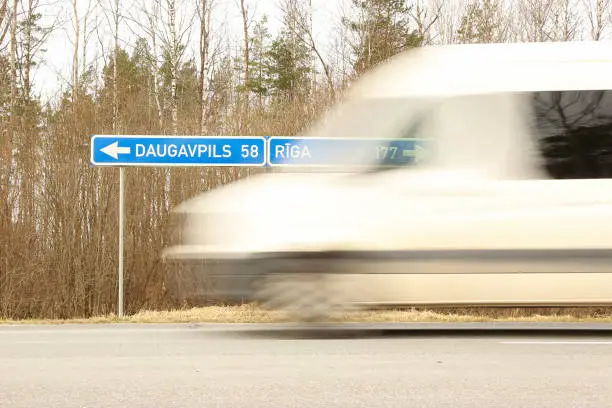 LIVANI DISTRICT, LATVIA - MARCH 19, 2020. car blurred on a highway and road sign Daugavpils - Riga