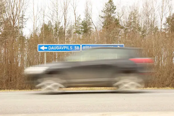 LIVANI DISTRICT, LATVIA - MARCH 19, 2020. car blurred on a highway and road sign Daugavpils - Riga