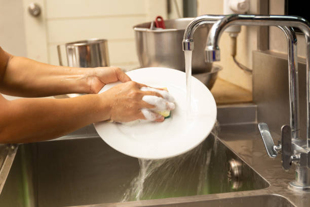 istock Hands washing dirty dishes with running water in kitchen sink. 1217110193