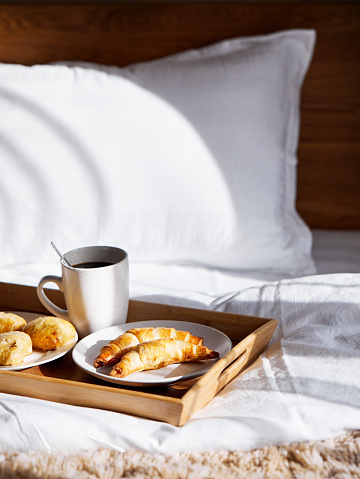 French croissants and black coffee on the tray in the bedroom on breakfast