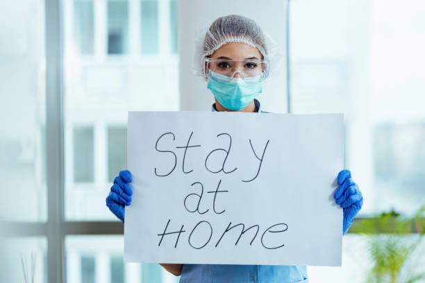 Stay at home! Female doctor holding placard with stay at home message as appeal for social distancing during a coronavirus epidemic. stay at home order stock pictures, royalty-free photos & images
