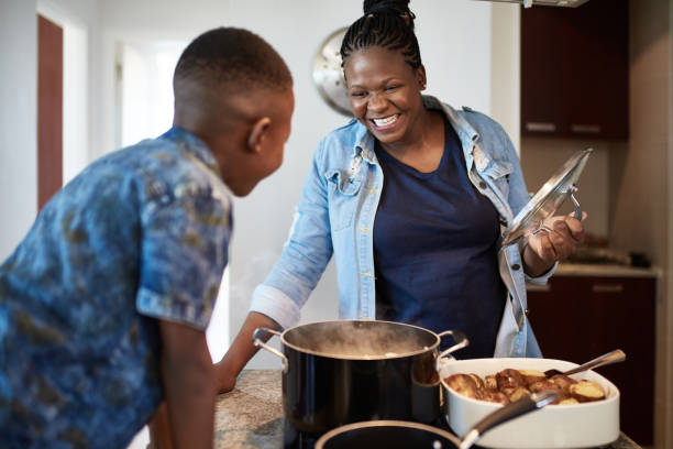 młody syn oglądanie afrykańska matka przygotować jedzenie - africa african descent cooking african culture zdjęcia i obrazy z banku zdjęć