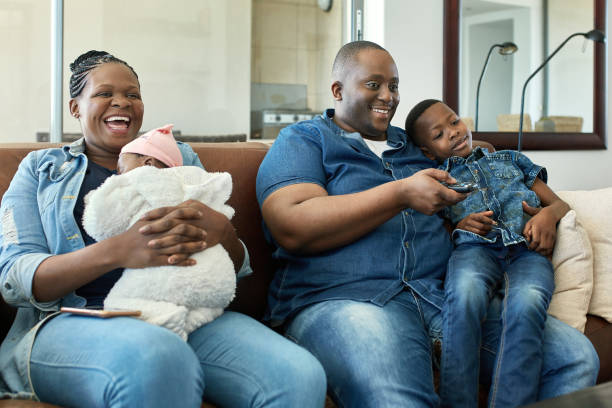istock Relaxed African with Two Children Watching TV at Home 1217111721