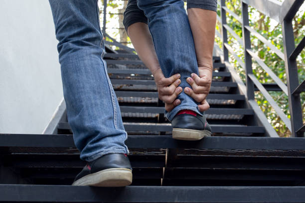 istock Man hand holding painful ankle while walking up the stairs. 1217113205