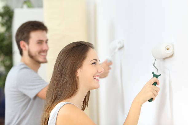 mur heureux de peinture de couples avec le rouleau de peinture à la maison - painting wall paint paint roller photos et images de collection