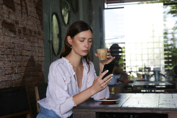istock Woman in cafe drinking coffee and using her mobile phone 1217114085