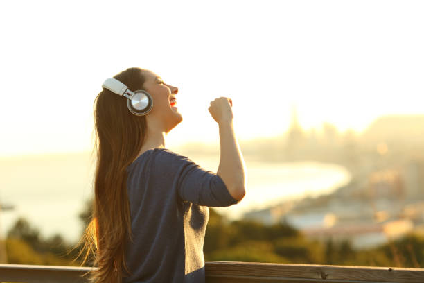 Girl singing listening music on headphones at sunset Happy girl singing listening music on headphones in a park at sunset free girl download stock pictures, royalty-free photos & images