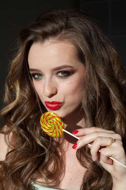 istock Beautiful woman with red lips eats a big candy sweet lollipop 1217114182