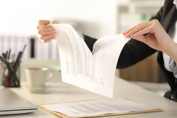 Close up of business woman hands breaking contract document sitting on a desk at the office