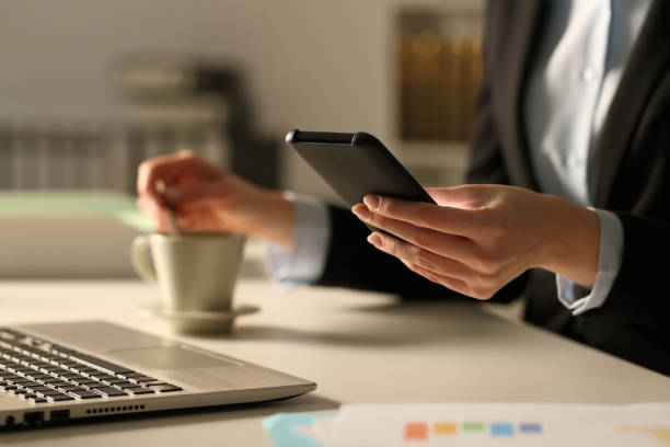 donna d'affari mani mescolando il telefono di controllo del caffè di notte - navigare in internet foto e immagini stock