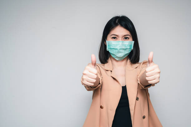 istock oman wearing face mask protect from virus showing thumb up 1217114600