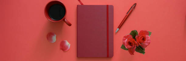 istock Top view of workspace with diary notebook, pen, coffee cup and rose vase on pink table 1217115325