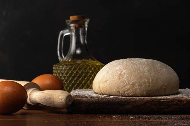 istock Fresh raw dough for bread or pizza with eggs on a dark wooden table. 1217118263