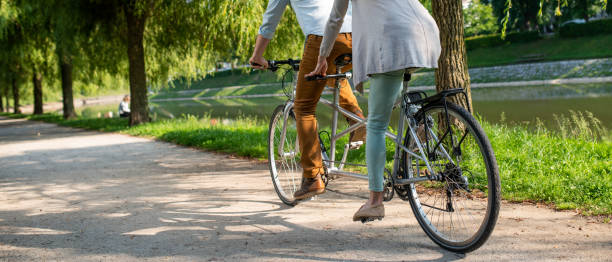 Couple riding tandem bicycle in park