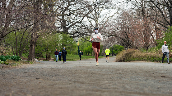 New York, NY, USA - April 5, 2020: New Yorkers wear masks due to the ongoing coronavirus pandemic as they walk and run on the bridle path encircling Manhattan’s Central Park Reservoir.