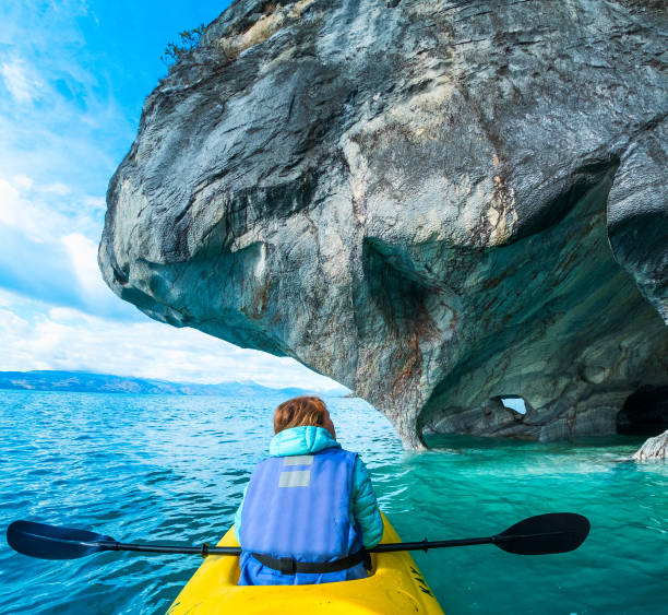 Woman paddles kayak Woman sits in kayak and explores the Marble Caves and rocks on the lake of General Carrera, Chile marble caves patagonia chile stock pictures, royalty-free photos & images