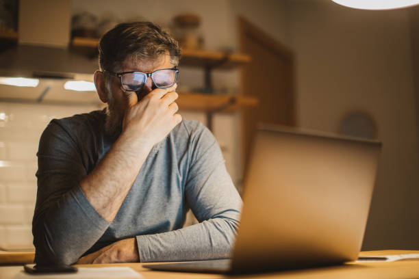 Working during isolation period Mature men at home during pandemic isolation reading something on laptop managing stress stock pictures, royalty-free photos & images