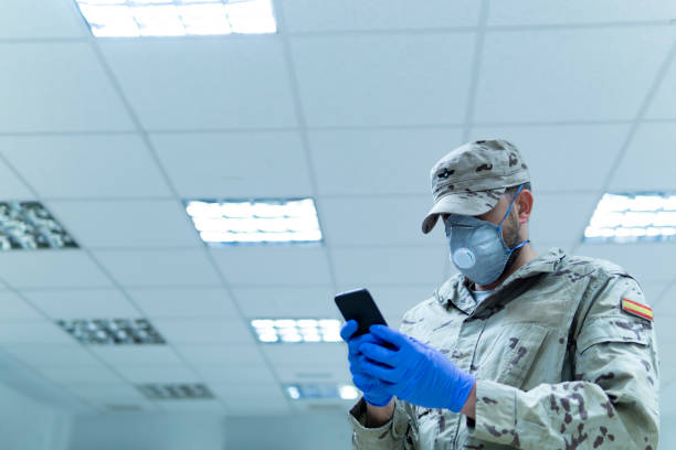 coronavirus. militar uniformado con su teléfono móvil y computadora portátil. - personal militar español fotografías e imágenes de stock